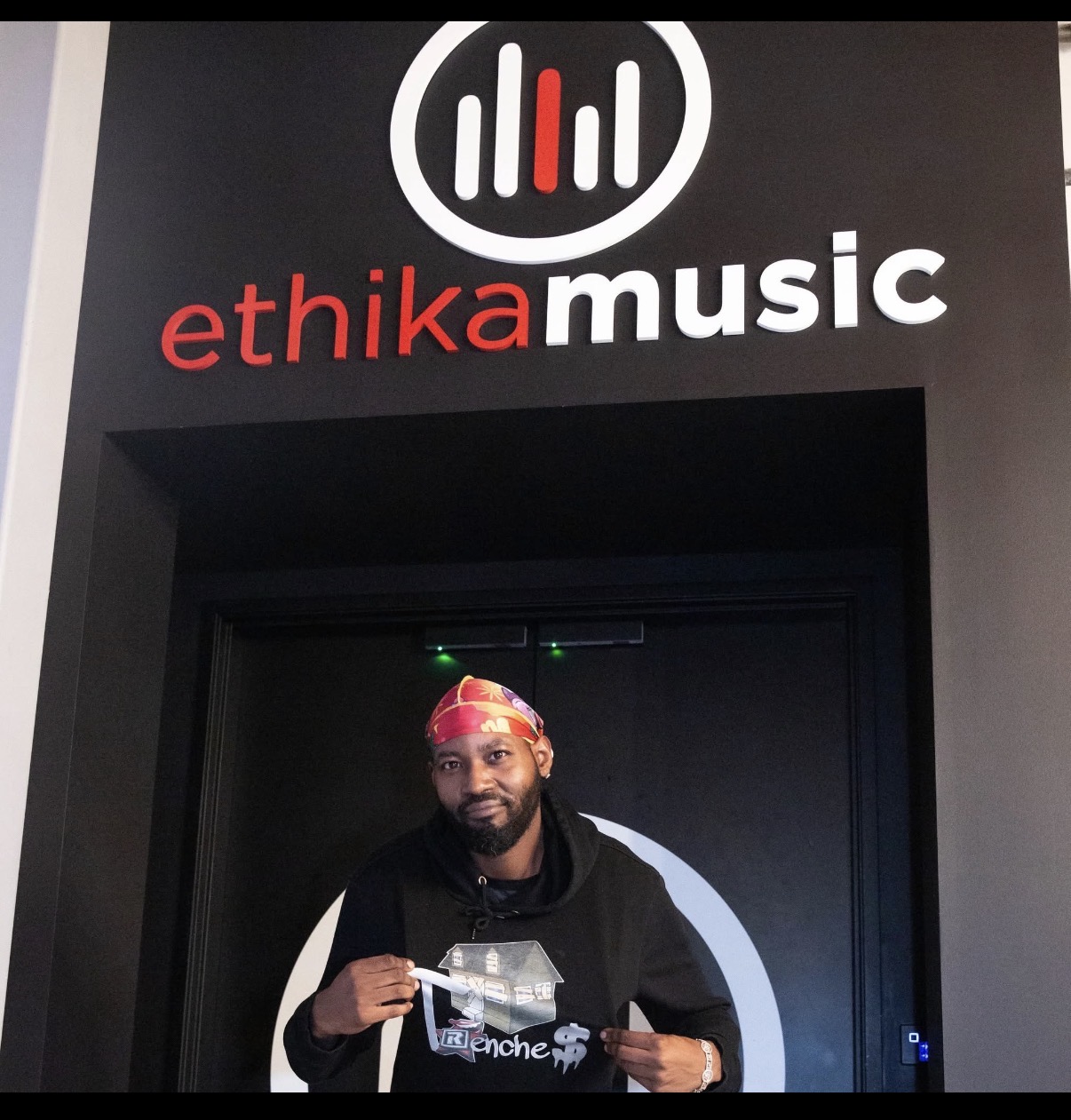 Flyboi Rich wearing a black hoodie and colorful head covering